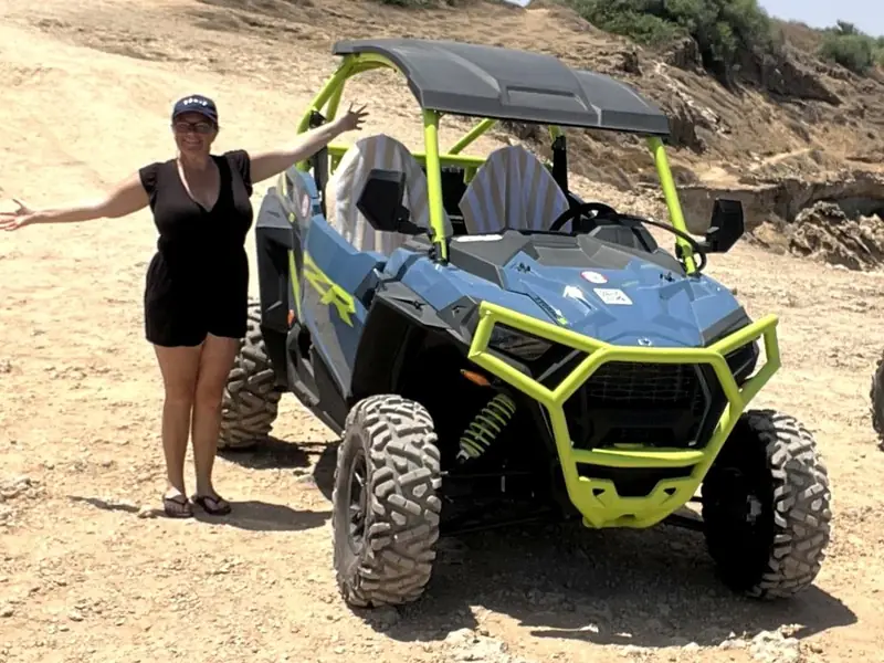 Philly, arms wide, beside an off-road buggy